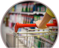 A light skinned person pushing a shopping cart down an aisle.